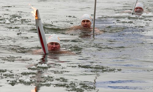 Torchbearer Alexander Brylin (left) swims with his torch in the company of other ice swimmers in the Amur River in Russia's Far Eastern city of Blagoveshchensk, some 5,600 kilometers east of Moscow. Russian torchbearers in October started the history's longest Olympic torch relay ahead of the Winter Olympic Games in Sochi. Photo: AFP