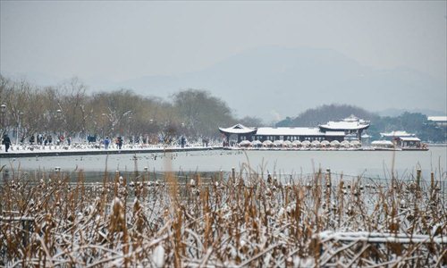 Tourists wonder by the West Lake after a snowfall in Hangzhou, capital of east China's Zhejiang Province, Feb. 8, 2013. A big range of snowfall enveloped Zhejiang Province on Friday. Photo: Xinhua