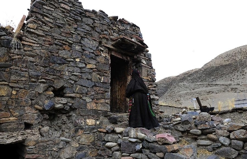 A hostess walks into a stone house which is aged over 600 years in Yangda Village of Riwar Township in Suoxian County in the Nagqu Prefecture, southwest China's Tibet Autonomous Region. Three stone houses, each with the age exceeding more than 600 years, are preserved well in the village. (Xinhua/Liu Kun)  