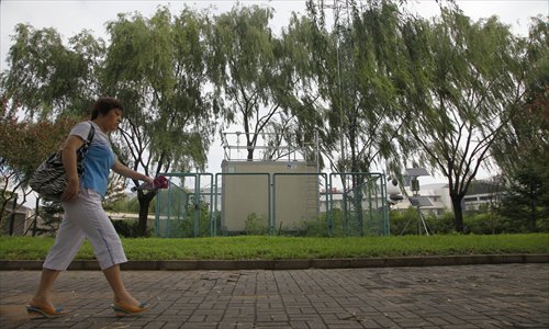 A resident walks past an air quality monitoring station set up in the Olympic Green, Beijing. Photo: CFP