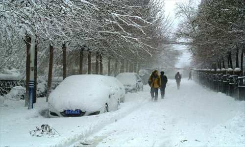 People walk on the snow-covered road in Hegang, northeast China's Heilongjiang Province, November 12, 2012. Heavy snowstorms have cut off regional power and water supplies as well as forced schools and highways to close in northeast China's Heilongjiang and Jilin provinces on Monday. Photo: Xinhua