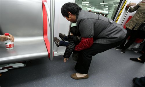 An elderly woman holds a urinating child on subway Line 1 in Hangzhou, Zhejiang Province Sunday. The subway, which opened for free trial runs, is expected to start full operations on Saturday. Photo: CFP