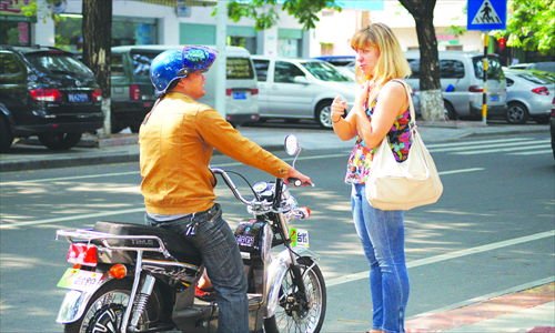 A foreigner negotiates with an electric motorcycle driver in the downtown area of Sanya, South China's Hainan Province Tuesday. Many local taxi drivers prefer to drive to well-known places of interest rather than the downtown areas as they can earn a commission from vendors in tourist areas. So local residents in the city use bicycles and motorcycles to get around instead. Photo: CFP 