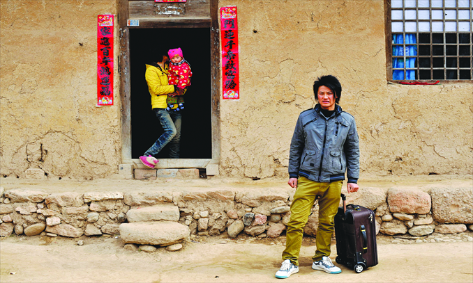 Yang Lijun, 30, stands outside his house with his wife and daughter. Photo: CFP