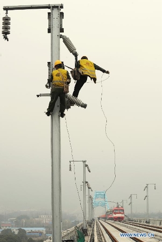 Two workers work on an electrification frame in Huzhou, east China's Zhejiang Province, March. 16, 2012. The 150-kilometer Hangzhou-Ningbo high-speed railway linking Hangzhou and Ningbo, two hub cities in Zhejiang, commenced its integration test here on Friday. Once put into operation on July 2013 as expected, the high-speed railway that designed at a top speed of 350km/h, would reduce the travel time to 36 minitues, a quarter time of the current two-hour journey. (Xinhua/Tan Jin)  