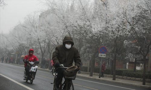 People ride along a Smog-shrouded street in Beijing, the capital of China, on January 29, 2013. The National Meteorological Center (NMC) issued a code-blue alert on January 27 as the smoggy weather forecast for the following two days would cut visibility and worsen air pollution in some central and eastern Chinese cities. Photo: Li Hao/GT