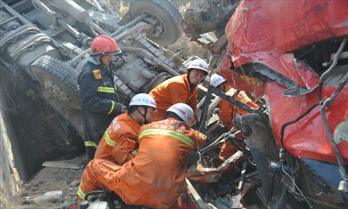 Rescuers try to pull a trapped passenger from the wreckage of a truck-bus collision on Wednesday in Wenshui county, Shanxi Province. Both vehicles plunged off a bridge, killing nine people and injuring 29 others. The cause of the crash is being investigated. Photo: IC