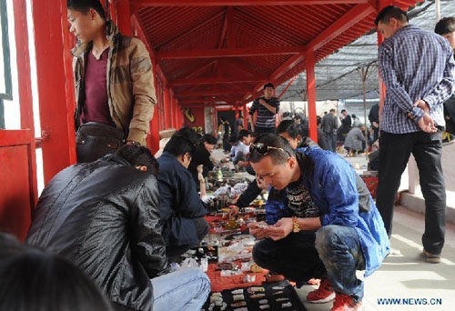 Customers choose curios at a flea market in Zhengzhou, capital of central China's Henan Province, April 14, 2012. The flea market of Zhengzhou Antique Market attracted many collectors everyday. Venders lay their goods on the ground, making the flea market a popular place for curios and antiques business. Photo: Xinhua