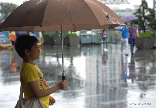 A boy holds an umbrella amid rain in Shenzhen, south China's Guangdong Province, May 26, 2013. Torrential rain hit most parts of Guangdong Province from Saturday to Sunday. (Xinhua/Mao Siqian)  