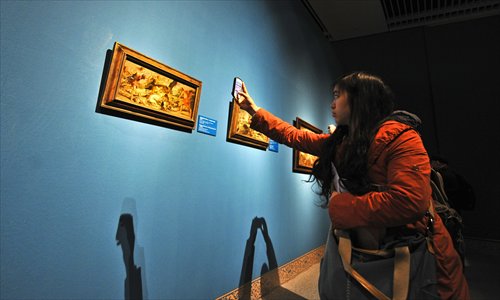 A female visitor uses her cell phone to take a picture of a painting on Tuesday at the National Museum of China in Beijing. Some 100 oil paintings, woodcuts and tapestries from the Liechtenstein collections, including works from Peter Paul Rubens and Anthony van Dyck, are exhibited in the museum until February 15, 2014. Photo: IC