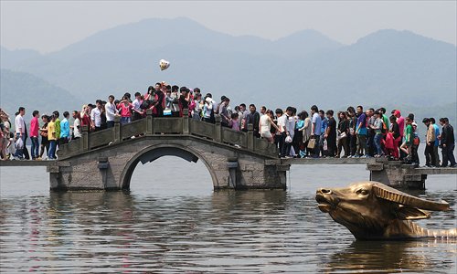 Tourists walk over a bridge at the West Lake in Hangzhou, Zhejiang Province, Wednesday, as the May Day holiday draws to an end. Photo: IC