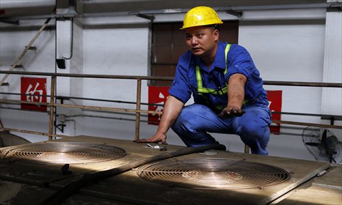 A subway maintenance worker checks the air conditioner on top of a train, where the temperature can rise as high as 60 C. Photo: CFP