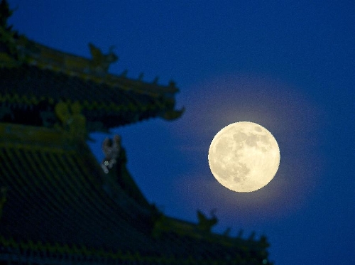 A full moon sets behind a building of the Forbidden City in Beijing, capital of China, June 23, 2013. The moon looks 14 percent larger and 30 percent brighter than usual on Sunday. The scientific term for the phenomenon is 