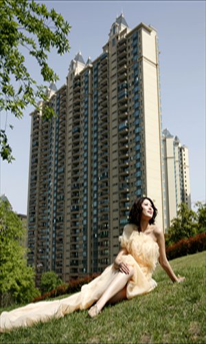 A model poses in a wedding dress in front of a newly constructed residential building in Yichang, Central China's Hubei Province Sunday. The apartment building developer held a wedding dress show to attract photographers and potential homebuyers. The average home price in the city reached 6,080 yuan ($982) per square meter last month, up 1.78 percent from the previous month, according to real estate consulting website cityhouse.cn. Photo: CFP 