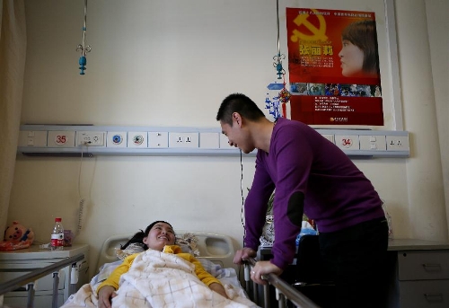 Zhang Lili, a teacher who lost her legs while saving two students from an onrushing bus, talks with her husband Li Ziye at the China Rehabilitation Research Center in Beijing, capital of China, Jan. 7, 2013. Zhang, who successfully pushed the students out of the harm's way but unable to avoid the bus herself and lost her legs in the accident, has been receiving rehabilitative treatment here for over 4 months. Zhang makes great efforts now in order to be able to walk again. (Xinhua/Jin Liwang) 