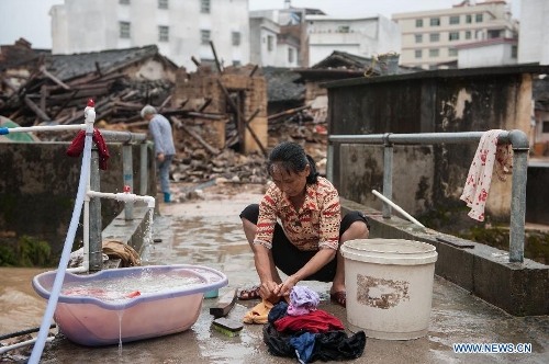 A villager washes clothes in front of houses destroyed by the rainstorm in Guangfu Town of Jiaoling County, Meizhou City, south China's Guangdong Province, May 22, 2013. Meizhou City was hit by a rainstorm on May 19, which killed one people and destroyed 951 houses, leaving 180, 000 people affected in Jiaoling County. (Xinhua/Mao Siqian)  