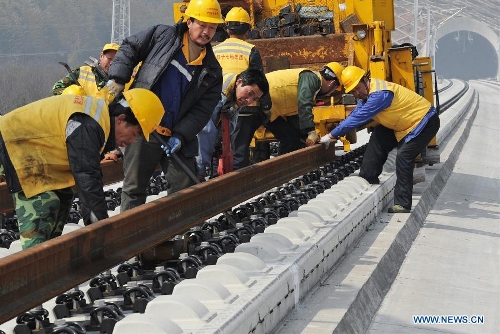 Construction workers and engineers examine rail tracks in the Huzhou Railway Station in Huzhou, east China's Zhejiang Province, March. 16, 2012. The 150-kilometer Hangzhou-Ningbo high-speed railway linking Hangzhou and Ningbo, two hub cities in Zhejiang, commenced its integration test here on Friday. Once put into operation on July 2013 as expected, the high-speed railway that designed at a top speed of 350km/h, would reduce the travel time to 36 minitues, a quarter time of the current two-hour journey. (Xinhua/Tan Jin)  