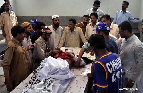 Pakistanis gather around the body of Sadiq Zaman Khattak, a candidate for a National Assembly seat of the ethnic Pashtoon 