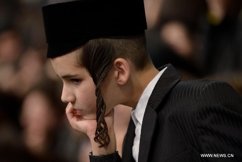 A Jewish boy of the Belz Hasidic Dynasty watches the wedding ceremony of Rabbi Shalom Rokeach, the grandson of the Belz Rabbi Yissachar Dov Rokeach ,at the neighbourhood of Kiryat Belz in Jerusalem on May 21, 2013. More than 10,000 Jews participated in the wedding. (Xinhua/Yin Dongxun) 