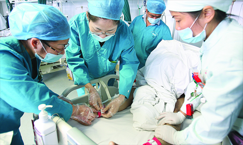 Yang Qi fastens a patient to the bed with other nurses, as she volunteers to experience what it's like being a nurse. Photo: IC