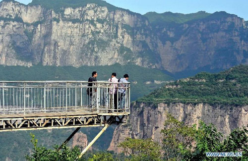 Tourists enjoy the scenery at Huilong Village in the Taihang Moutains in Huixian County, central China's Henan Province, June 14, 2012. Huilong Village was a poor residential area in the early 1990s. In 2000, an eight-kilometer highway and tunnels of a total length of 1,000 meters were built on the cliffs for the village's development. The village took the advantage of its mountainous scenery to develop tourism industry, increasing the residents' incomes and improving their life. Photo: Xinhua