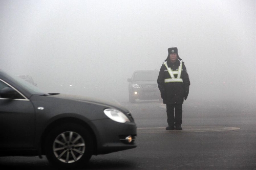 A traffic policeman is on guard in fog in Bazhou City, north China's Hebei Province, Jan. 22, 2013. (Xinhua/Wang Geming) 