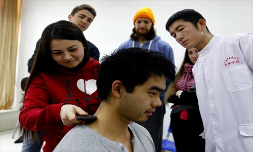 Elvira Azinbekova, from Kazakhstan, practices guasha scraping therapy in a class. 