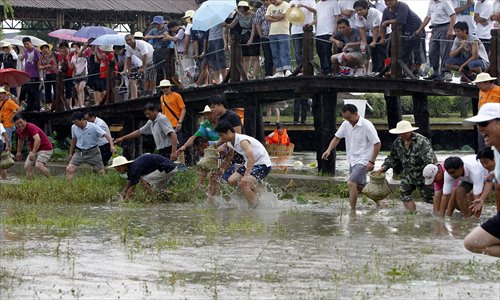 Dozens of  contestants scramble to grab fish from a pond at a farmer sports meet in Jinshan district Saturday. More than 200 people from eight districts  competed in the event, which aimed to promote farming practices and develop agricultural tourism. Photo: Xinhua