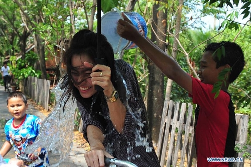 A boy pours a bucket of water on a woman during celebrations for Songkran Festival, Thailand's traditional New Year Festival, at the Ancient City in Samut Prakan Province, Thailand, April 14, 2013. Songkran, also known as the Water Splashing Festival, started here on April 13 this year. (Xinhua/Rachen Sageamsak)