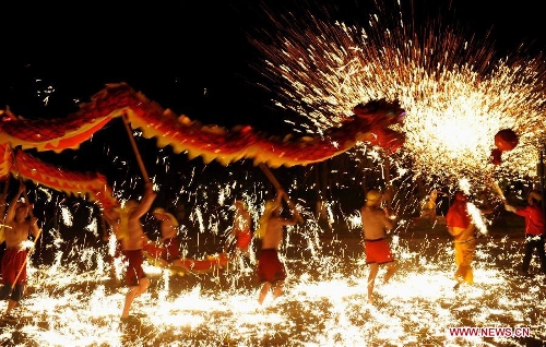 Actors perform dragon dance in firecrackers at the Daguan Park in Kunming, capital of southwest China's Yunnan Province, Feb. 6, 2013. The dance, as a derivative of traditional dragon dance in which performers hold dragon on poles and walk through floods of firecrackers, is a state intangible cultural heritage. (Xinhua/Lin Yiguang) 