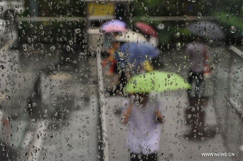 Pedestrians walk amid rain in Shenzhen, south China's Guangdong Province, May 26, 2013. Torrential rain hit most parts of Guangdong Province from Saturday to Sunday. (Xinhua/Mao Siqian)  