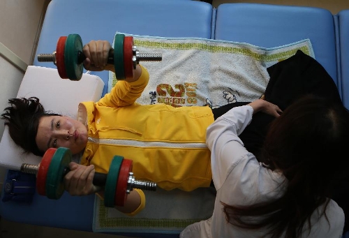 Zhang Lili, a teacher who lost her legs while saving two students from an onrushing bus, does rehabilitative training under the help of a doctor at the China Rehabilitation Research Center in Beijing, capital of China, Jan. 7, 2013. Zhang, who successfully pushed the students out of the harm's way but unable to avoid the bus herself and lost her legs in the accident, has been receiving rehabilitative treatment here for over 4 months. Zhang makes great efforts now in order to be able to walk again. (Xinhua/Jin Liwang) 