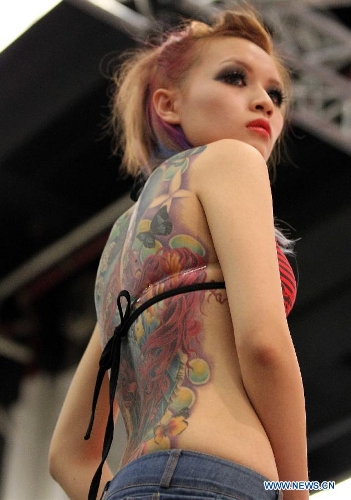 A woman from Asia shows her tattoo during the 21st International Tattoo Convention in Frankfurt, Germany, March 22, 2013. The Tattoo Convention kicked off on Friday and will last for three days. (Xinhua/Luo Huanhuan)