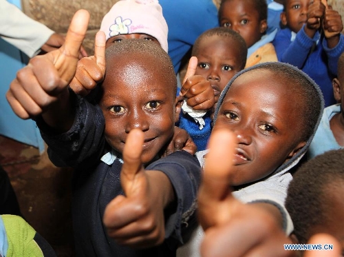 Pupils gather to welcome reporters at Mcedo Beijing School in Nairobi, capital of Kenya, April 11, 2013. Mcedo Beijing School is located in Mathare slum, one of the largest slums in Kenya and home to about 500,000 residents. The school offered mathematics, English, Swahili, science and some other courses for over 600 students living in three nearby regions. Pupils got free lunch in the school thanks to the United Nations World Food Programme. (Xinhua/Meng Chenguang) 