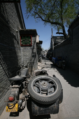 A motorcylce in the Hutong(Photo: CRIENGLISH.com/ Wang Zhi)A Hutong is a traditional alley, characteristic of an old Beijing city. A total of 7000 Hutongs have been built throughout the capital in straight lines under strict construction guildlines. The longest Hutong starts from the Beijing Legation Quarter, Dong Jiao Min Xiang,to the Xijiao Min Xiang, and has a total length of 6.5 kilometers, while the shortest Hutong is One-inch Street at only several meters' long. The narrowest Hutong is only about 0.7 meters wide. Therefore, people carrying even a little bit of extra weight have to hold their breath to pass through it. Formed during the Yuan, Ming and Qing, dynasties thousands of Hutongs surround the supreme Imperial Palace from all directions. They are woven into the fabric of people's daily lives.