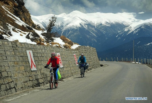 Photo taken on April 15, 2013 shows two cyclers riding along a highway in Nyingchi Prefecture, southwest China's Tibet Autonomous Region. (Xinhua/Wen Tao) 