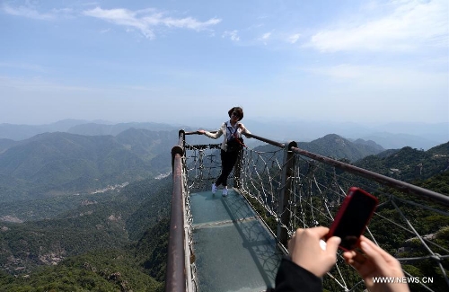 A tourist poses for photo in the Sanqing Mountain in east China's Jiangxi Province, April 13, 2013. The scenic area of Sanqing Mountain entered a peak tourist season as temperature rises recently. (Xinhua/Zhou Ke)  