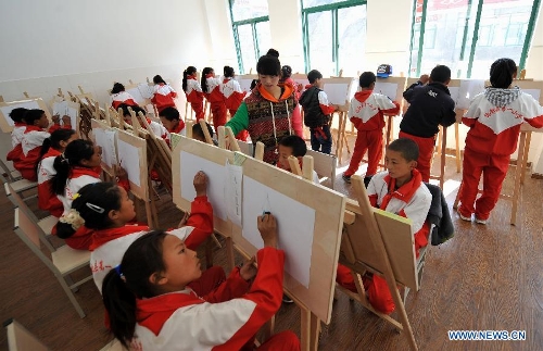 A teacher (C) of the Tibetan ethnic group gives an art class at No. 1 Primary School of Deqin County in Diqing Tibetan Autonomous Prefecture, southwest China's Yunnan Province, March 12, 2013. A total of 1,260 pupils, most of whom are of the Tibetan ethnic group, study at this school, which was founded in September 2012. Pupils here are offered free meals and lodging. (Xinhua/Lin Yiguang) 