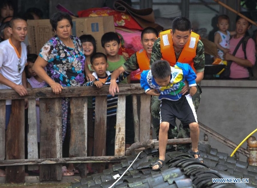 Firemen help evacuate a child in Tongnan County of Chongqing, southwest China's municipality, July 1, 2013. Rainstorm-triggered natural disasters have hit nine provincial-level regions since June 29, leaving at least 39 dead and another 13 missing, China's Ministry of Civil Affairs (MCA) said Monday. The National Meteorological Center (NMC) issued a blue alert for rainstorms on Monday, forecasting heavy rain to continue in parts of north and southwest China over the next three days. The NMC also warned of downpours, thunderstorms and hail in south China's coastal Guangdong province and the island province of Hainan, which are bracing for approaching tropical storm Rumbia. (Xinhua/Liu Chan)