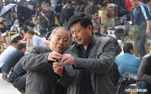 Customers choose curios at a flea market in Zhengzhou, capital of central China's Henan Province, April 14, 2012. The flea market of Zhengzhou Antique Market attracted many collectors everyday. Venders lay their goods on the ground, making the flea market a popular place for curios and antiques business. Photo: Xinhua