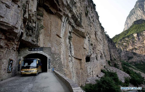 A shuttle bus moves on a way towards a scenic area at Huilong Village in the Taihang Moutains in Huixian County, central China's Henan Province, June 14, 2012. Huilong Village was a poor residential area in the early 1990s. In 2000, an eight-kilometer highway and tunnels of a total length of 1,000 meters were built on the cliffs for the village's development. The village took the advantage of its mountainous scenery to develop tourism industry, increasing the residents' incomes and improving their life. Photo: Xinhua