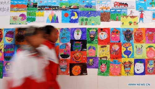 Pupils of the Tibetan ethnic group walk past the painting works of their schoolmates at No. 1 Primary School of Deqin County in Diqing Tibetan Autonomous Prefecture, southwest China's Yunnan Province, March 12, 2013. A total of 1,260 pupils, most of whom are of the Tibetan ethnic group, study at this school, which was founded in September 2012. Pupils here are offered free meals and lodging. (Xinhua/Lin Yiguang)  