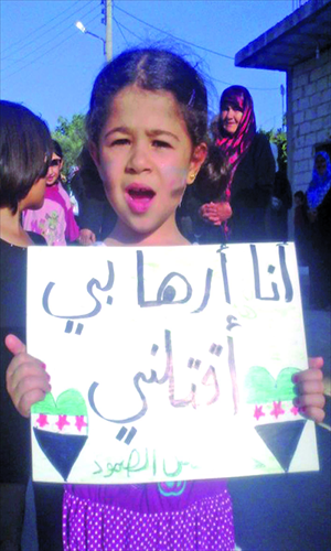 A handout picture released by the Syrian opposition's Shaam News Network shows a girl holding a placard with Arabic writing which reads, 