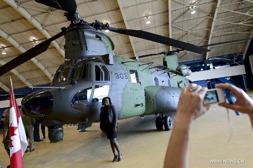 A woman poses beside a new CH-147F Chinook helicopter during the unveiling ceremony in Ottawa June 27, 2013. The 15 newly purchased F-model Chinooks will be engaged in support, domestic and foreign operations for the Royal Canadian Air Force's reactivated 