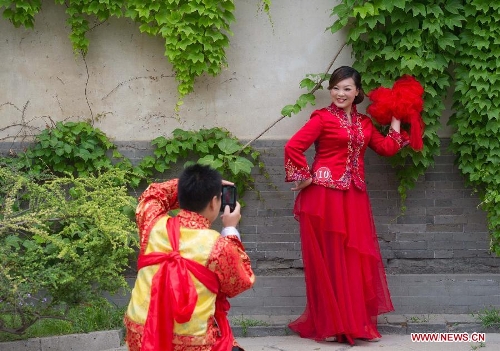 A groom takes photos of his bride during a group wedding held in the Old Summer Palace, or Yuanmingyuan park, in Beijing, China, May 18, 2013. A total of 30 couples of newlyweds took part in event with traditional Chinese style here on Saturday. (Xinhua/Luo Xiaoguang)  