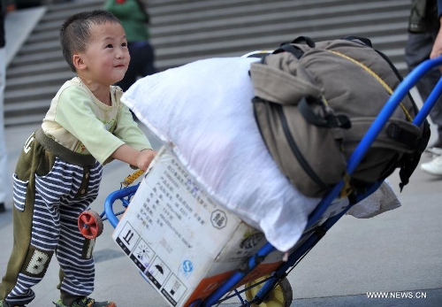 A little boy helps his family push the luggage case at Nanning train station in Nanning, capital of south China's Guangxi Zhuang Autonomous Region, Feb. 3, 2013. Many children travel with their families during the 40-day Spring Festival travel rush which started on Jan. 26. The Spring Festival, which falls on Feb. 10 this year, is traditionally the most important holiday of the Chinese people.Public transportation is expected to accommodate about 3.41 billion travelers nationwide during the holiday, including 225 million railway passengers. (Xinhua/Zhou Hua)