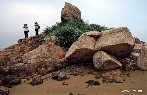 Two visitors take pictures at the Ping Chau Island in south China's Hong Kong, May 12, 2013. Ping Chau, also named Tung Ping Chau, lies in the northeast corner of Hong Kong and is part of the Hong Kong Geopark. The island is home to shale rocks in various shapes which makes it a popular tourist attraction. (Xinhua/Chen Xiaowei)  