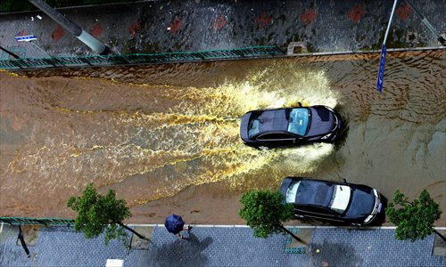 Two cars make bow waves as they surge through the water on Zhennan Road, Putuo district. Photo: Cai Xianmin/GT