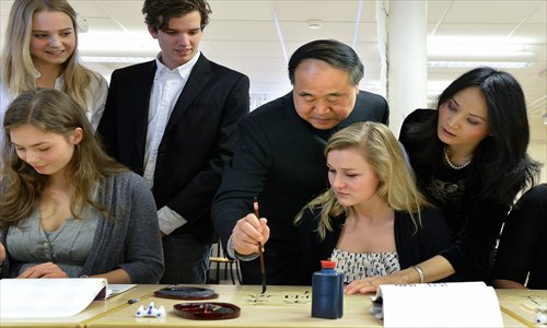 The 2012 Nobel Prize in Literature winner Mo Yan (with brush) demonstrates Chinese calligraphy to students during a visit at Hersby Gymnasium high school in Lidingo, outside Stockholm, Sweden, on Friday. Mo delivered a literature lecture at the Swedish Academy on Saturday. Photo: CFP