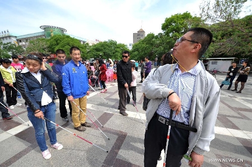 A worker helps the blind people to walk with a crutch by giving out whistle signals at the Yuhuangge Square in Yinchuan City, capital of northwest China's Ningxia Hui Autonomous Region, May 14, 2013. An activity aimed at helping the blind to walk was held here on Tuesday, in which more than 100 blind people were provided with crutches as they were helped to walk with them ahead of the 23rd national day for helping the disabled on May 19. (Xinhua/Peng Zhaozhi) 